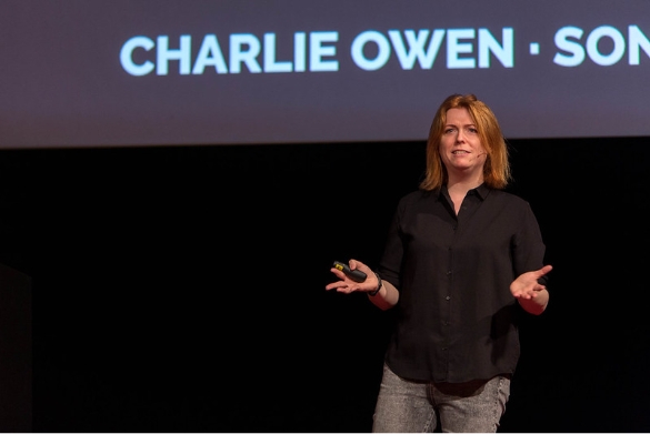 image de la conférenciére charlie owen, elle se tient debout devant ses slides